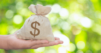 A person's outstretched arm holding a large money bag in their open hand