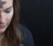 A person praying with eyes closed with Ash Wednesday cross on their forehead