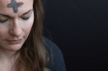 A person praying with eyes closed with Ash Wednesday cross on their forehead