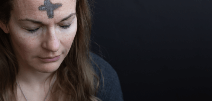 A person praying with eyes closed with Ash Wednesday cross on their forehead