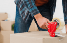 Person using a tape gun to seal a moving box