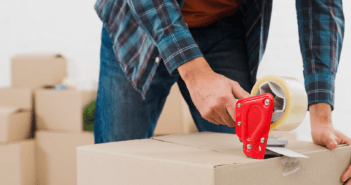 Person using a tape gun to seal a moving box