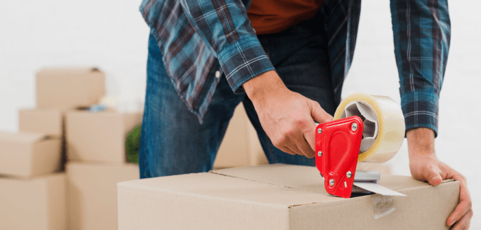 Person using a tape gun to seal a moving box