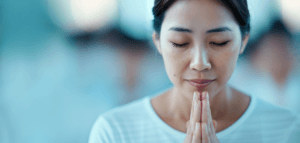 Person with their eyes closed and hands together in prayer