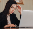 Person at a desk looking uneasily at a laptop computer