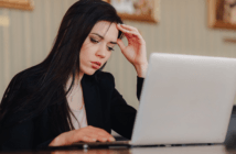 Person at a desk looking uneasily at a laptop computer