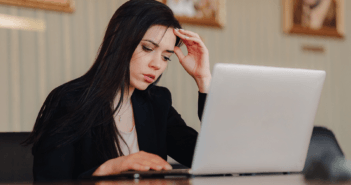 Person at a desk looking uneasily at a laptop computer