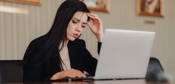 Person at a desk looking uneasily at a laptop computer