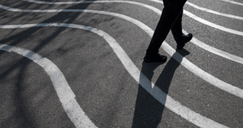 Person and their shadow walking on pavement painted with wavy lines