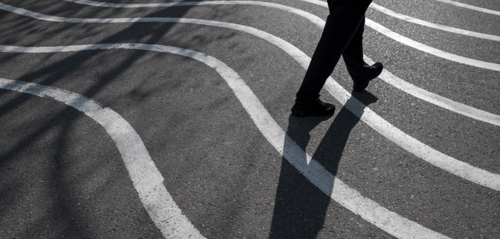Person and their shadow walking on pavement painted with wavy lines