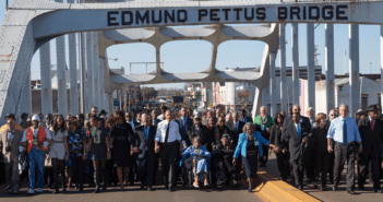 President Obama, congressman John Lewis, former President George W. Bush, and Civil Rights Movement veterans and other commemoration attendees marching across the Edmund Pettus Bridge in March 2015.