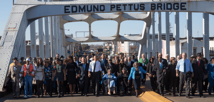 President Obama, congressman John Lewis, former President George W. Bush, and Civil Rights Movement veterans and other commemoration attendees marching across the Edmund Pettus Bridge in March 2015.