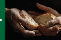 The hands of two people together holding slices of rustic bread