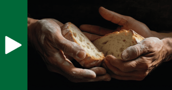 The hands of two people together holding slices of rustic bread