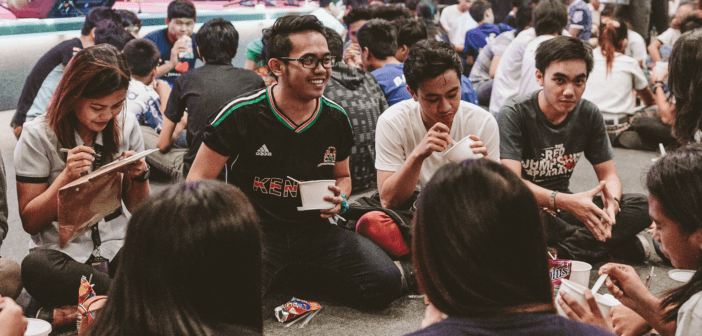 Youth sitting on the floor in circles laughing and enjoying snacks together