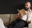 Person on the couch with their feet up reading a book