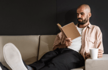 Person on the couch with their feet up reading a book