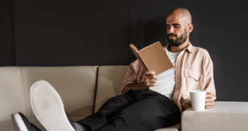 Person on the couch with their feet up reading a book