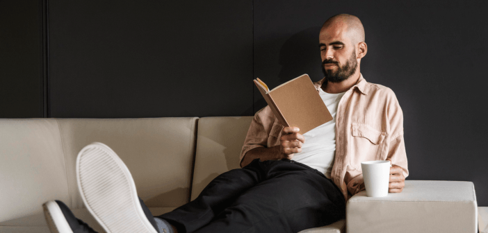 Person on the couch with their feet up reading a book