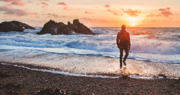 Person walking alone on the beach at sunset