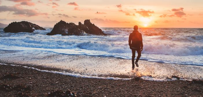Person walking alone on the beach at sunset