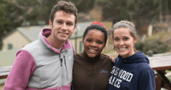 Three smiling teenagers outside on a mission trip to the country