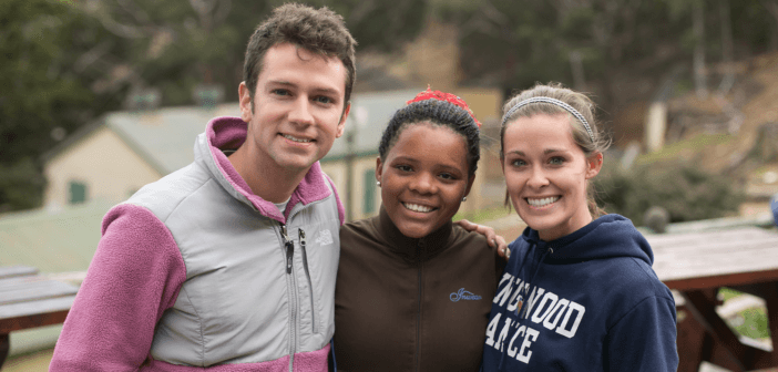 Three smiling teenagers outside on a mission trip to the country