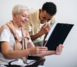 Older person in a wheelchair smiling while sharing information with a younger team member
