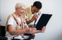 Older person in a wheelchair smiling while sharing information with a younger team member