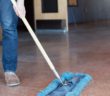 Person using a push broom to sweep the church floor