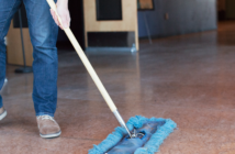 Person using a push broom to sweep the church floor