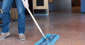 Person using a push broom to sweep the church floor