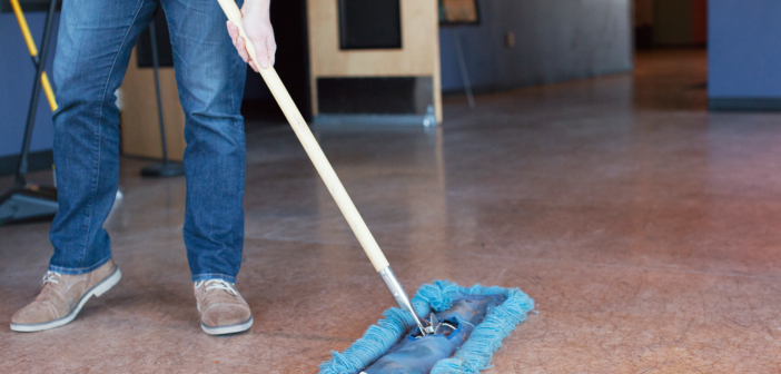 Person using a push broom to sweep the church floor