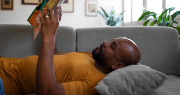 Person lying on the couch reading a book