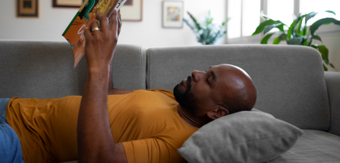 Person lying on the couch reading a book