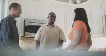 Smiling people in the kitchen at an informal church gathering in someone's house