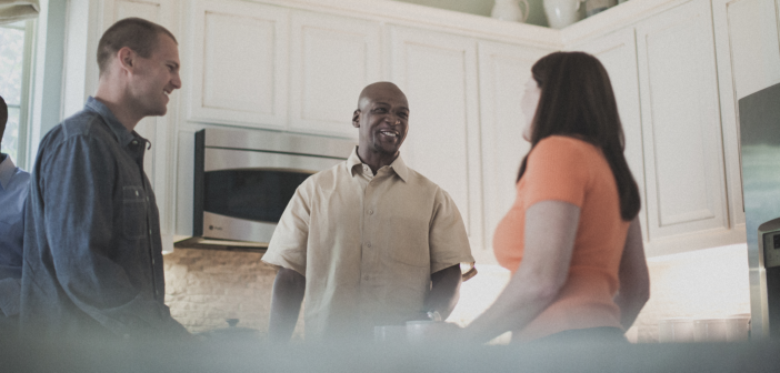 Smiling people in the kitchen at an informal church gathering in someone's house