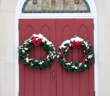 Christmas wreaths hanging on a church's front doors.