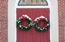 Christmas wreaths hanging on a church's front doors.