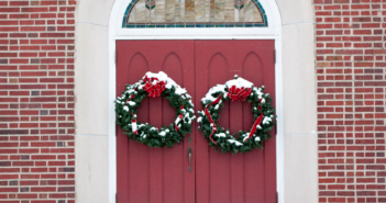 Christmas wreaths hanging on a church's front doors.