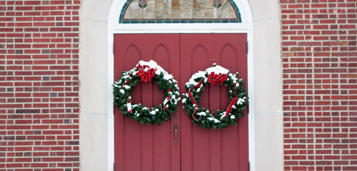 Christmas wreaths hanging on a church's front doors.