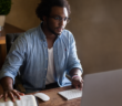 Person using a computer while referencing a Bible