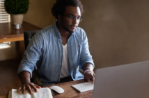Person using a computer while referencing a Bible