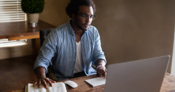 Person using a computer while referencing a Bible