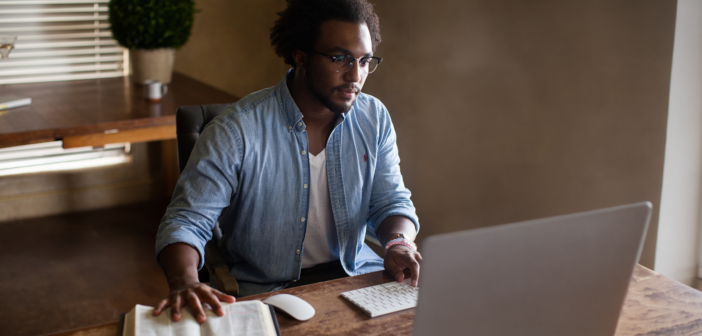 Person using a computer while referencing a Bible
