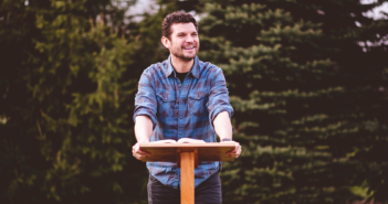 Friendly younger pastor preaching a sermon outdoors