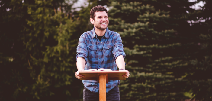 Friendly younger pastor preaching a sermon outdoors