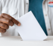 Person dropping their vote into the ballot box