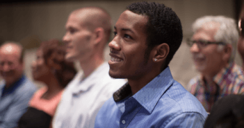 Smiling person sitting in a pew at a worship service